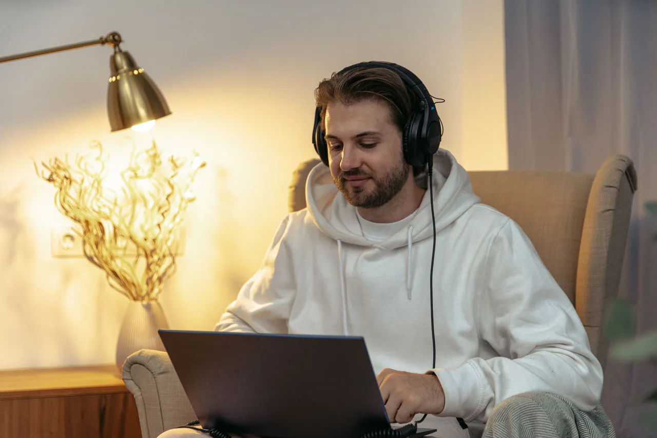 A creator working on a laptop with headphones in warm light